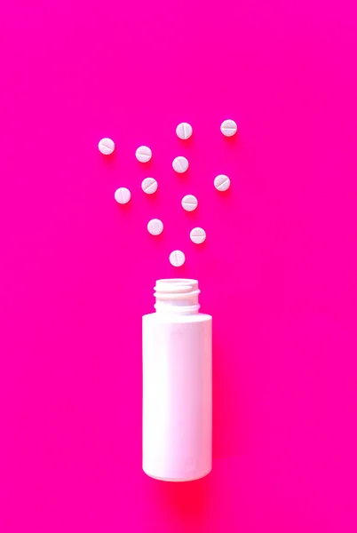Белые таблетки или таблетки с упаковкой на розовом фоне с копировальным пространством — стоковое фото