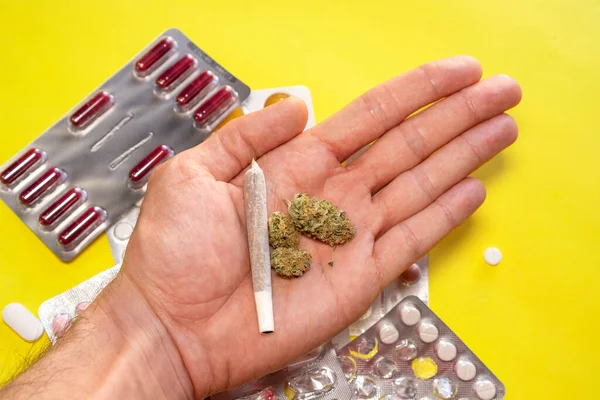 Mão com cannabis no fundo com comprimidos. Conceito de cannabis medicinal. — Fotografia de Stock