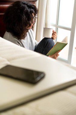 Sakin kadın evde kitap okumak için telefon ve teknoloji kullanmayı bırakıyor..