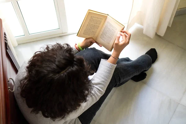 Çıplak ayaklı bir kadının yerde oturup evde kitap okuduğu en iyi manzara..