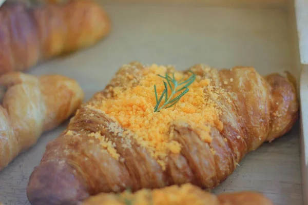 Bread croissant topped with crispy powder and decorated with romery leaves