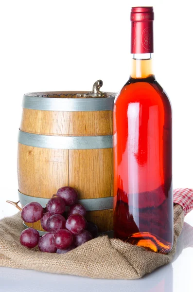 Botella de vino con uvas tintas y un barril en una bolsa de arpillera — Foto de Stock