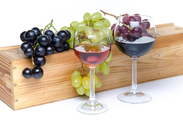 Glasses of wine in front of a wooden box with grapes — Stock Photo, Image