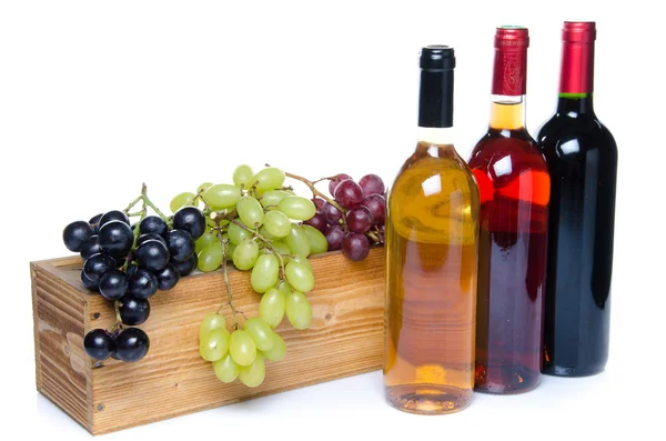 Bottles of wine in front of a wooden box with grapes — Stock Photo, Image