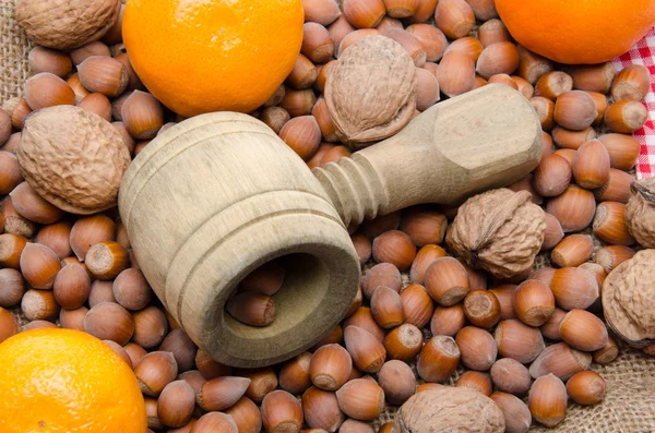 Notenkraker, hazelnoten, mandarijnen en walnoten op een jute zak — Stockfoto