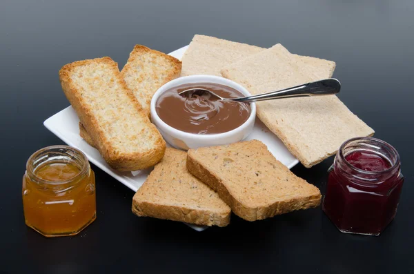 Composition of chocolate hazelnut spread, jams and different rus — Stock Photo, Image