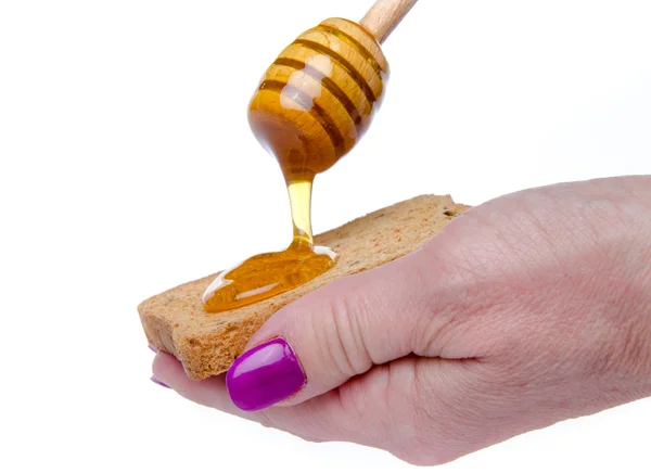 Woman's hand holding a toast with honey flowing from a  honey dipper — Stock Photo, Image