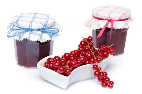 Röda vinbär i en liten skål och två burkar av röda vinbär sylt — Stockfoto