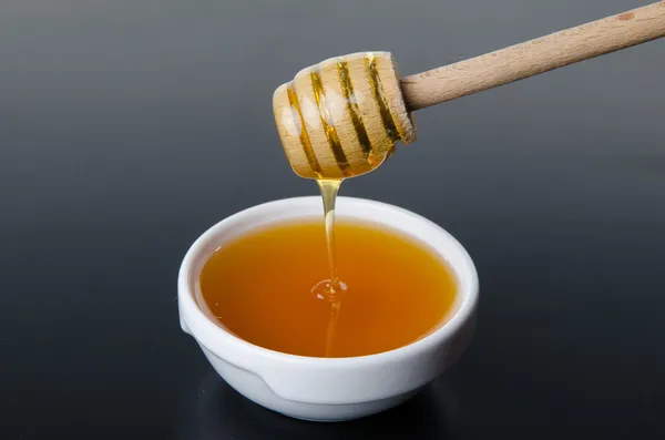 Honey flowing from a  honey dipper — Stock Photo, Image