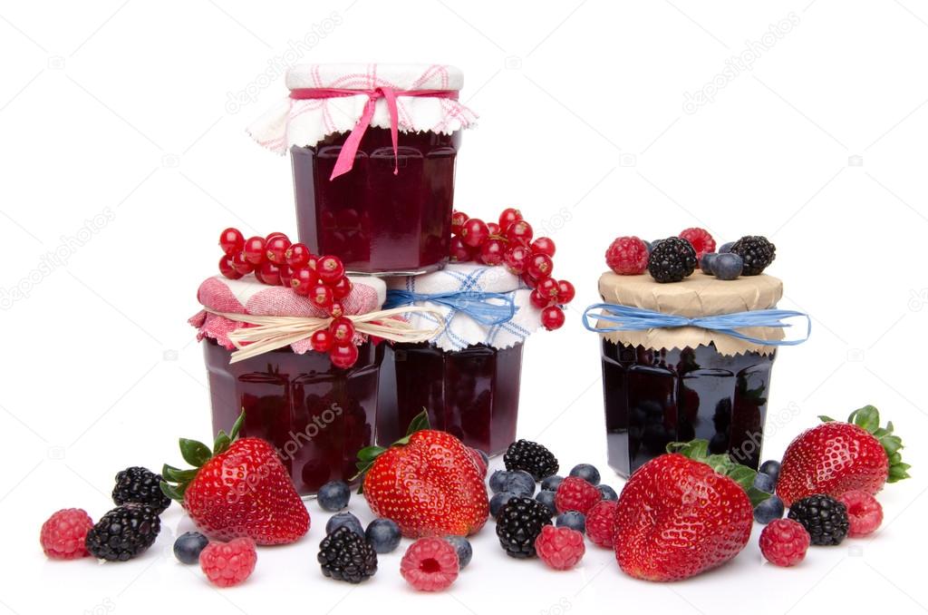 Composition with jars of red and black fruits jams and fresh fru