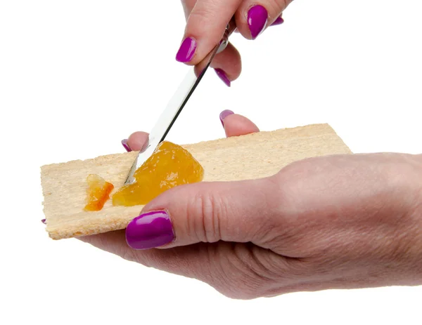 Mano de mujer extendiendo mermelada de naranja en un brindis — Foto de Stock