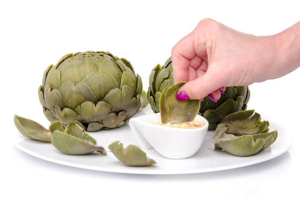 Die Hand einer Frau taucht ein Artischockenblatt in eine Vinaigrette — Stockfoto