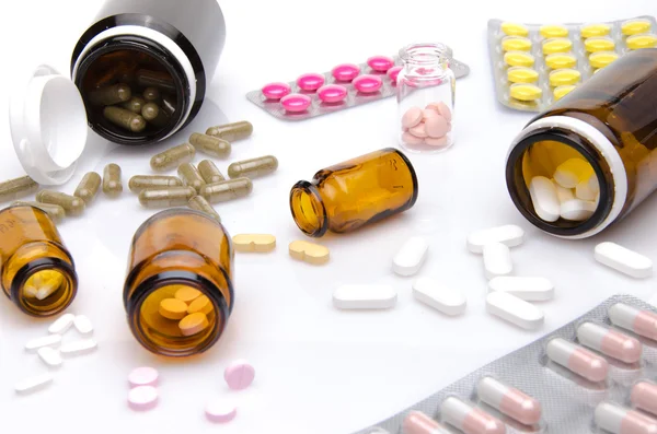 Comprimidos e cápsulas derramando fora do frasco pílula — Fotografia de Stock
