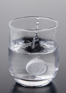 Effervescent tablet falling into a glass of water clipart