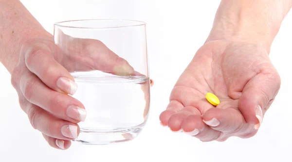 Hands holding a pill and a glass of water — Stock Photo, Image