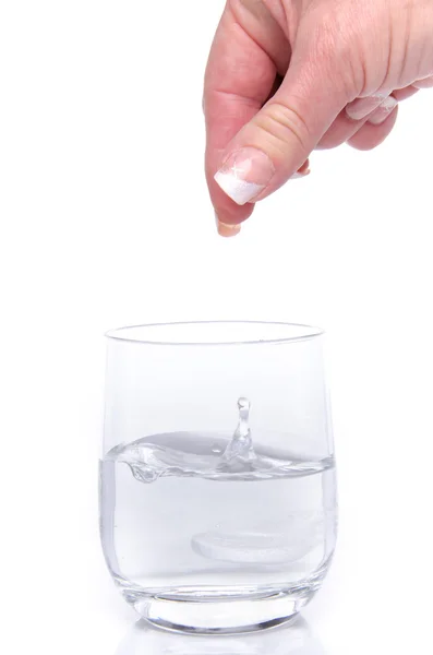 Hand dropping a tablet in a glass — Stock Photo, Image