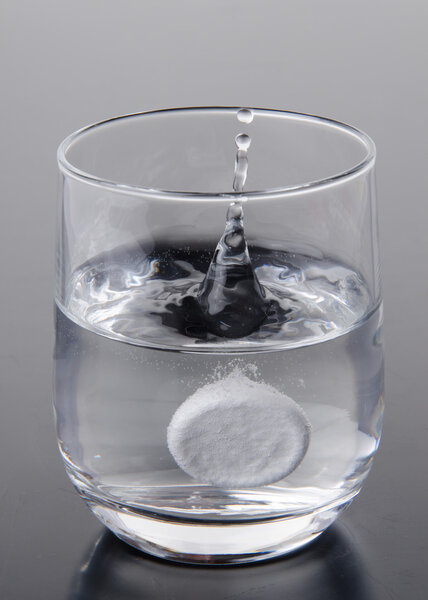 Effervescent tablet falling into a glass of water