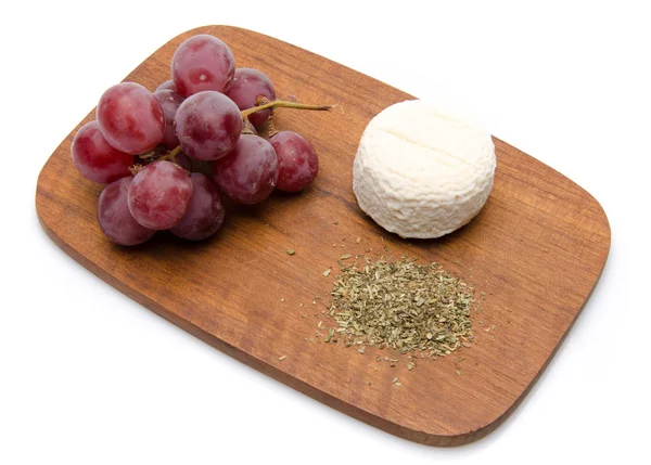 Goat cheese, grapes and provencal herbs on a wooden cutting boar — Stock Photo, Image