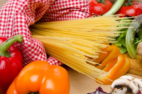 Composição de espaguete não cozido cercado por legumes — Fotografia de Stock