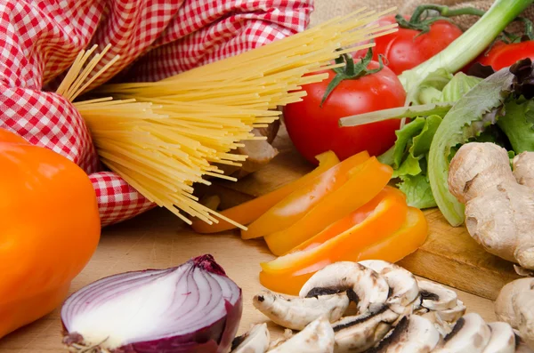 Composición de espaguetis sin cocer rodeados de verduras —  Fotos de Stock