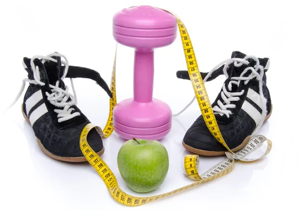Розовый гантель, яблоко и спортивная обувь с рулеткой — стоковое фото
