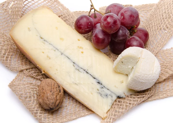 Cheeses and grapes on a burlap — Stock Photo, Image