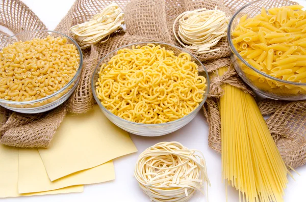 Different types of uncooked pasta on a burlap — Stock Photo, Image