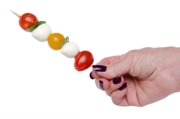 Mão segurando um espeto de tomate cereja e mussarela — Fotografia de Stock