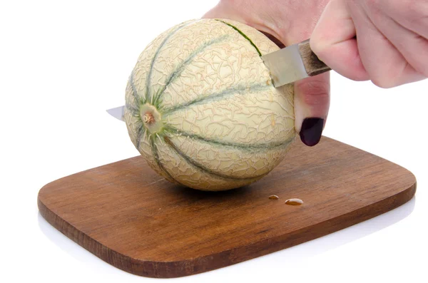 Coupe à la main d'un melon sur une planche de bois — Photo