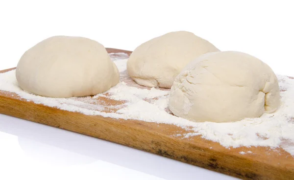 Drie ballen van pizza deeg op een houten bord — Stockfoto