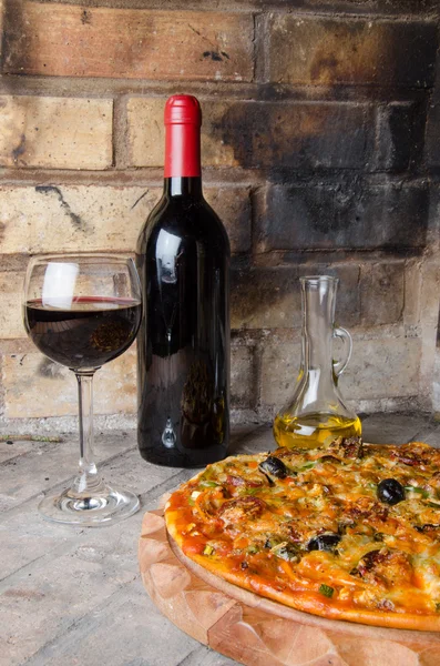 Pizza with wine and oil on a firebricks background — Stock Photo, Image