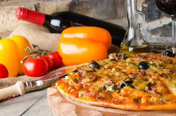 Pizza com vinho e alguns ingredientes em um fundo de tijolos — Fotografia de Stock