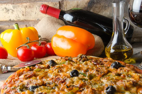 Pizza with wine and some ingredients on a firebricks background — Stock Photo, Image