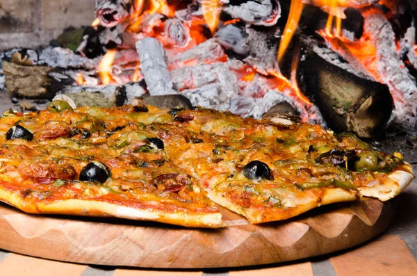 Pizza in front of a fire — Stock Photo, Image