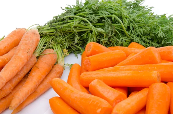 Bunch of fresh carrots and heap of peeled carrots — Stock Photo, Image