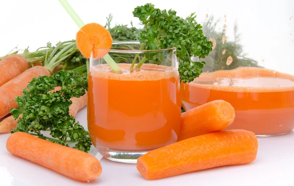 Σύνθεση με ένα ποτήρι και μια κανάτα χυμού καρότου, φρέσκα καρότα Εικόνα Αρχείου