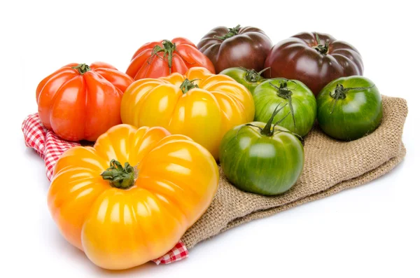 Green, yellow, orange and purple tomatoes on a burlap — Stock Photo, Image
