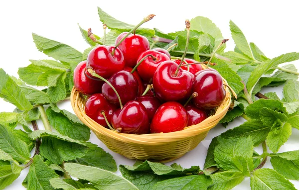 Composition with cherries in a basket surrounded with mint — Stock Photo, Image