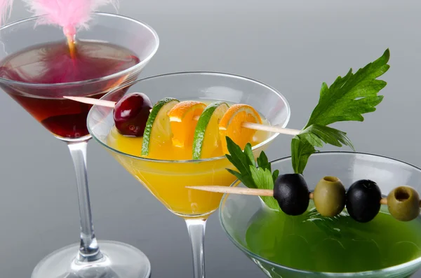 Cocktails aus Orangen, Kirschen und grünem Gemüse auf grauem Hintergrund — Stockfoto