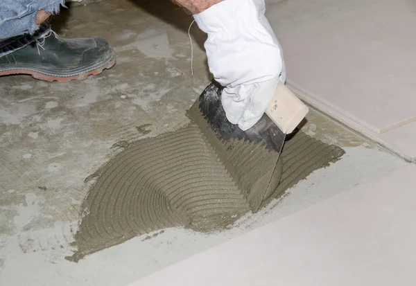 Tiler espalhando adesivo de telha no chão — Fotografia de Stock