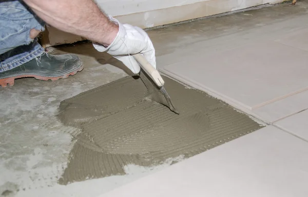 Tiler esparcir adhesivo de baldosas en el suelo — Foto de Stock