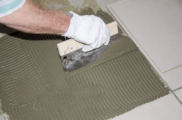 Tiler spreading tile adhesive on the floor — Stock Photo, Image