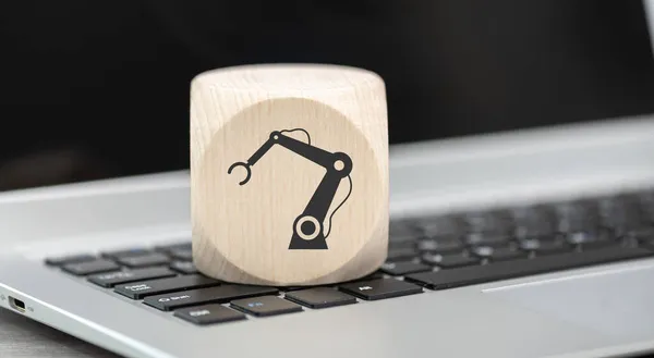 Wooden block with symbol of robotic industry concept on laptop keyboard
