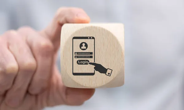 ログインコンセプトのシンボルを持つ木製のキューブを保持手 — ストック写真