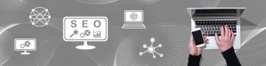 Dizüstü bilgisayar ve seo konsepti sembollü cep telefonu kullanan ellerin üst görünümü