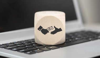 Wooden block with symbol of money transfer concept on laptop keyboard