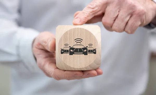コネクティッドカーのコンセプトを象徴する木製のキューブを手で握る — ストック写真