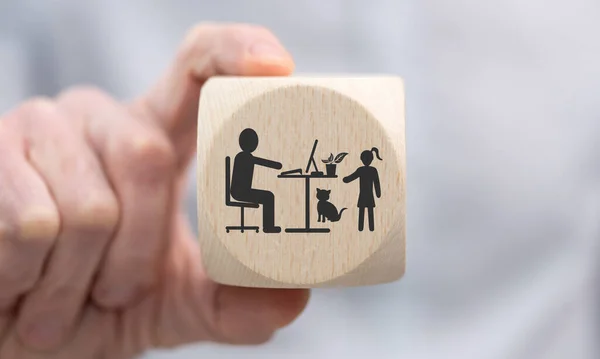 手拿着一个木制立方体 上面印有家庭办公概念的符号 — 图库照片