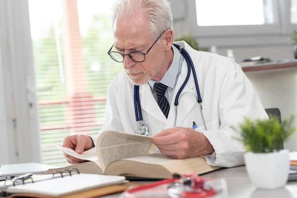 Ανώτερος Γιατρός Διαβάζει Ένα Εγχειρίδιο Στο Ιατρικό Γραφείο — Φωτογραφία Αρχείου