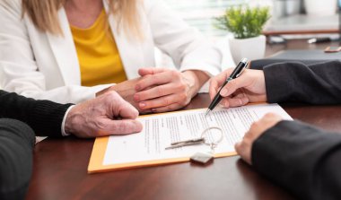 Female realtor giving explanation to a couple about terms of investment contract(Lorem ipsum text used)